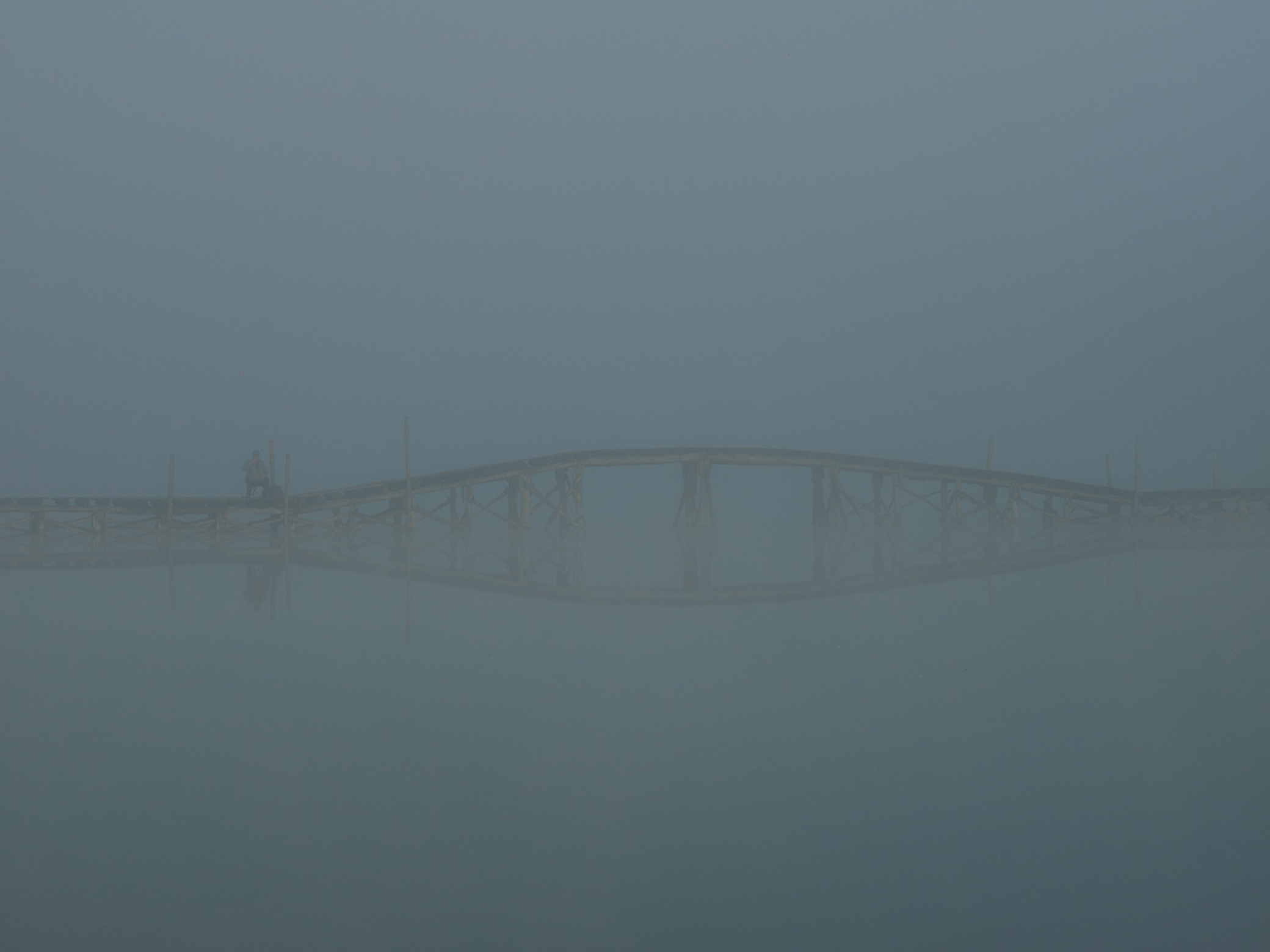 Рыбак на мосту в тумане