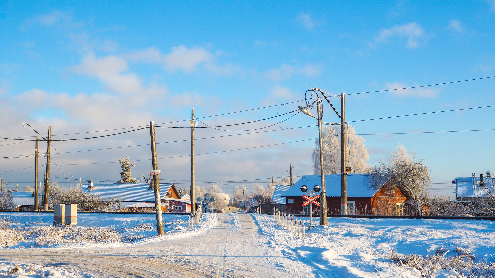 Железнодорожный переезд в солнечный морозный день на окраинах старинного русского города Гатчина.